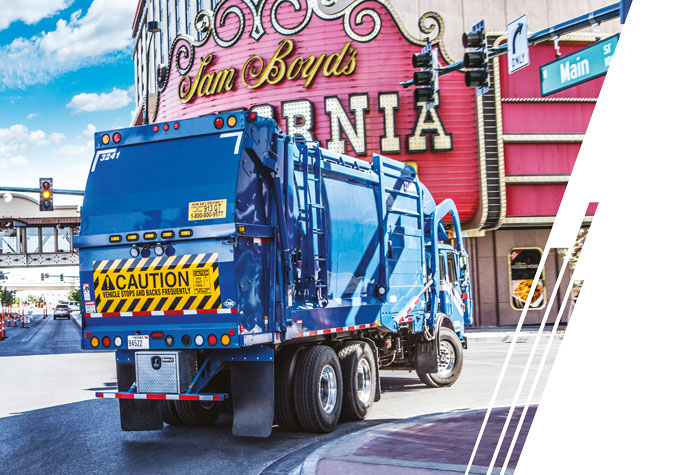 A blue refuse truck turns right onto a street in Las Vegas.